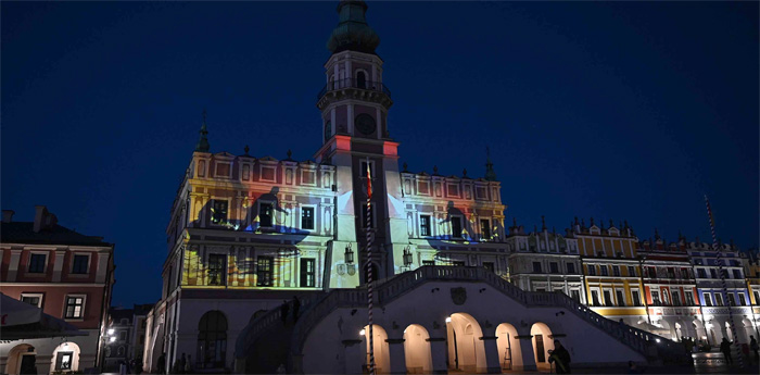 Mapping animacji na Zamojskim Ratuszu. Ratusz wraz z przyległymi kamieniczkami pokazany w szerszym ujęciu