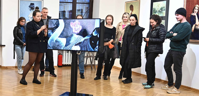 Na pierwszym planie widoczny monitor z wyświetloną animacją, w tle uczestnicy 2 edycji Programu Edukacyjnego Multimedia dla Ilustracji